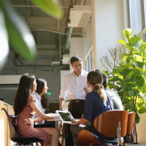 A group of young adults gathered around a table in a comfortable room, engaged in a dynamic conversation about financial literacy, demonstrating their interest and active involvement in understanding personal finance.