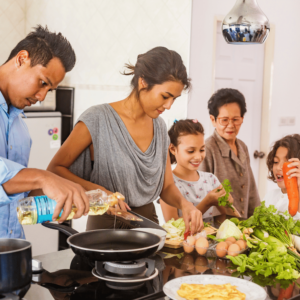 A multi-generational Singaporean family happily preparing a meal together in the kitchen, symbolizing the security and well-being that comes with understanding and utilizing types of insurance such as CPF, MediShield Life, and Integrated Plans.