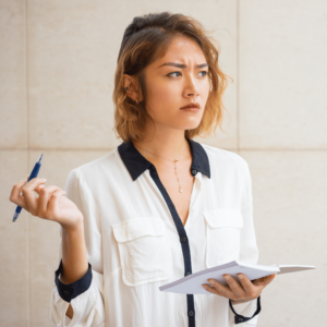 A young woman standing, holding an opened notebook and pen, lost in deep thought as she looks into the distance. The image symbolizes the contemplation and strategic thinking involved in mastering budgeting skills and planning for financial stability.