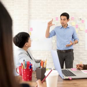 Young professionals attentively listened to a financial coach discussing debt management strategies in a bright conference room, displaying finance-related data on a whiteboard.