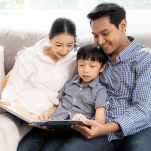 A Singaporean family spending quality time together in their living room, engaging in budget-friendly activities such as reading a book to their son. A reflection of their commitment to budget-conscious living.