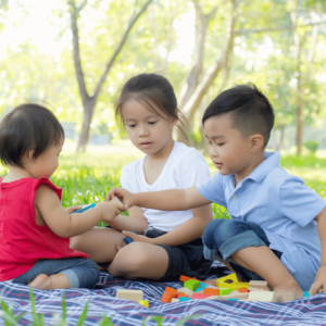 Three joyful children playfully engaging in a park in Singapore, symbolizing the contentment and financial freedom achieved through smart budgeting techniques.