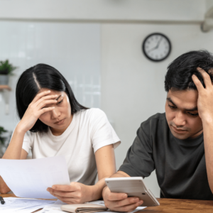 Concerned couple meticulously reviewing financial documents in their kitchen, exemplifying the necessity for diverse insurance types as a means of securing financial stability and protection in unforeseen circumstances.