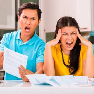 A young couple sitting at a table, looking stressed and overwhelmed by a pile of bills and receipts, symbolizing financial challenges